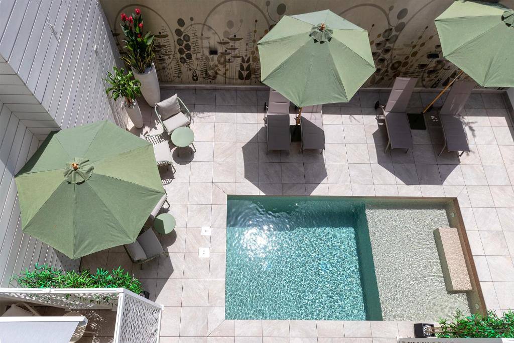 an overhead view of a swimming pool with umbrellas and chairs at Mesbeglia Luxury Rooms in Alghero