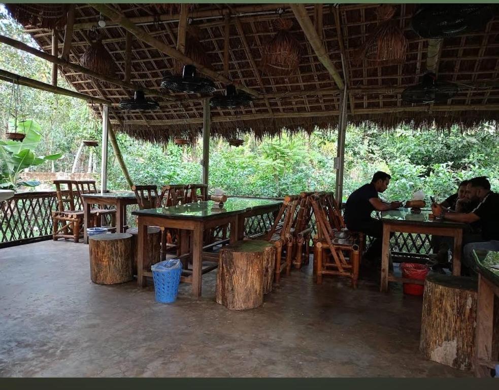 a group of people sitting at tables in a restaurant at Nishorgo Nirob Eco Resort in Sreemangal