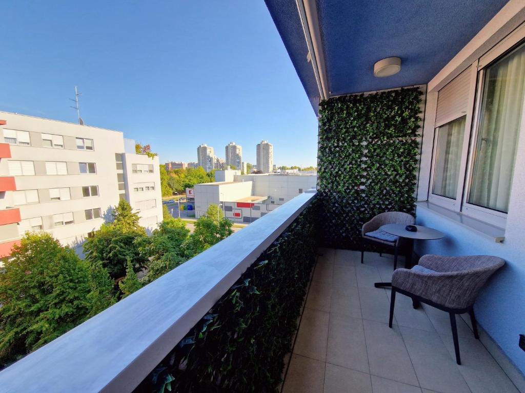 a balcony with a green wall and two chairs at Studio apartment Zen Zagreb with free garage in Zagreb