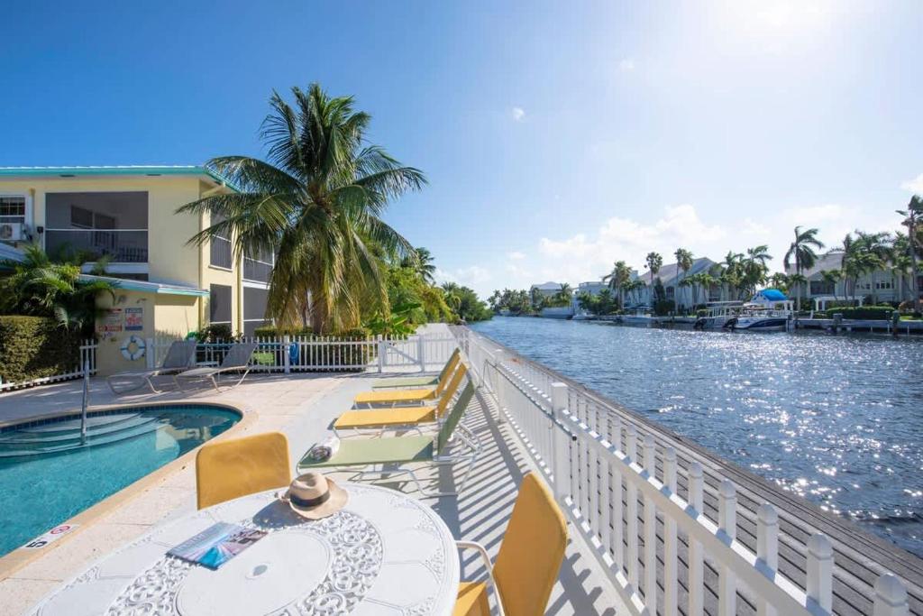 a balcony with a table and chairs next to a body of water at Snug Harbour View Condo #5 in George Town