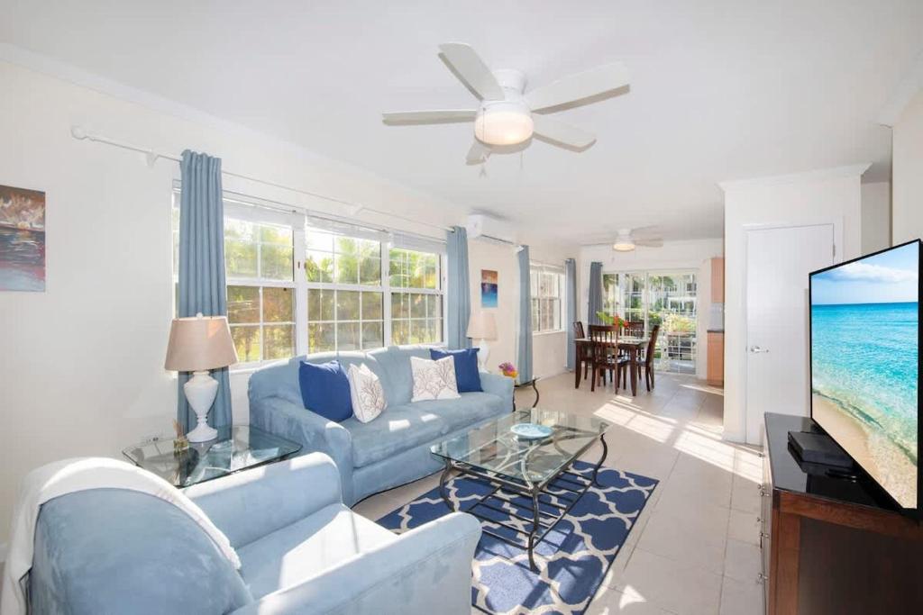 a living room with a blue couch and a tv at Snug Harbour View Condo #1 in George Town