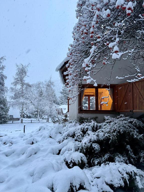 a house covered in snow in front of it at Nevada Hostel in San Carlos de Bariloche