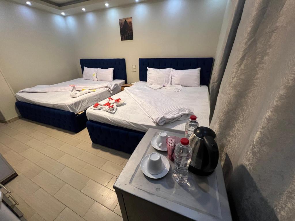 a hotel room with two beds and a table with drinks at Osiris pyramids in Cairo