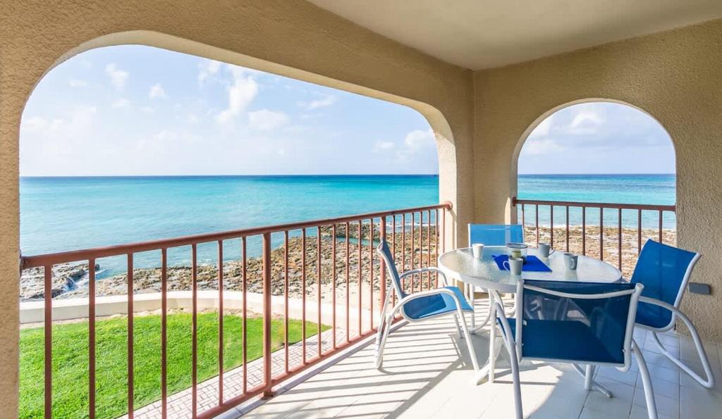 ein Balkon mit Tisch und Stühlen und dem Meer in der Unterkunft Georgetown Villas #201 in George Town