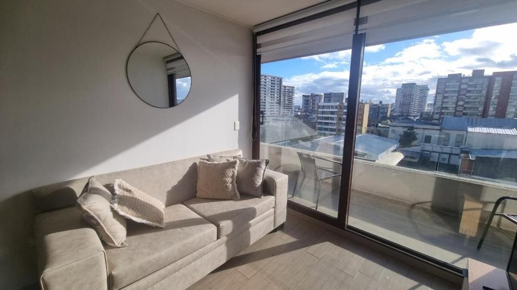 a living room with a couch and a large window at Comodidad y ubicación perfecta in Temuco