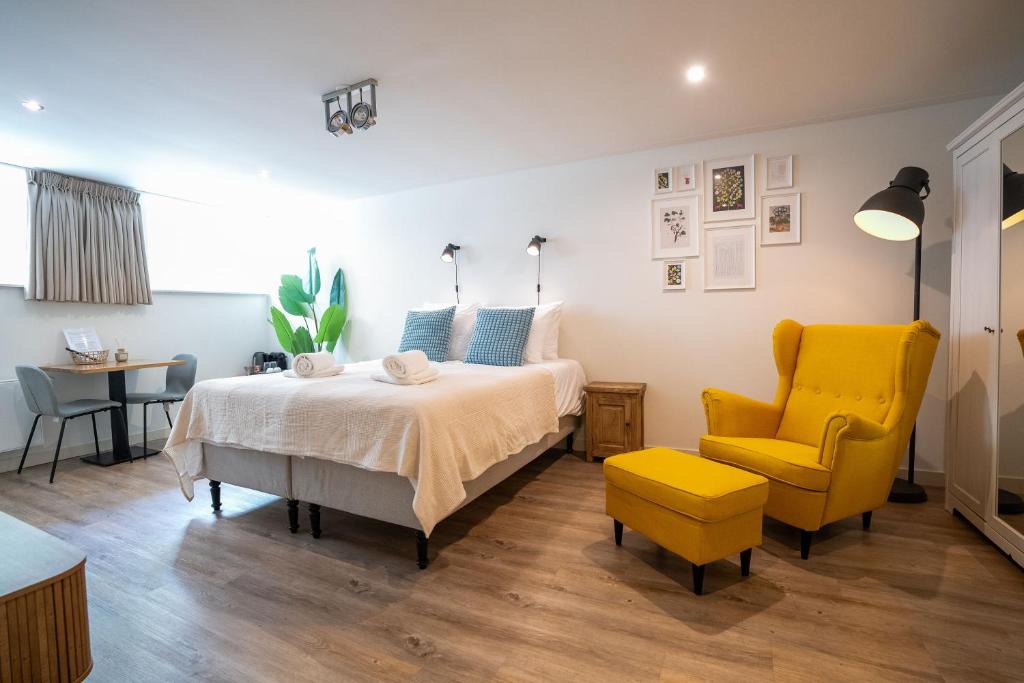 een slaapkamer met een bed en een gele stoel bij Nassau Canal Suites - in the heart of the city in Amsterdam