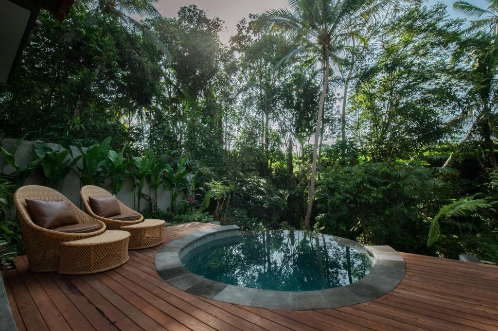 a hot tub on a wooden deck with two chairs at Shaka bali villa in Ubud
