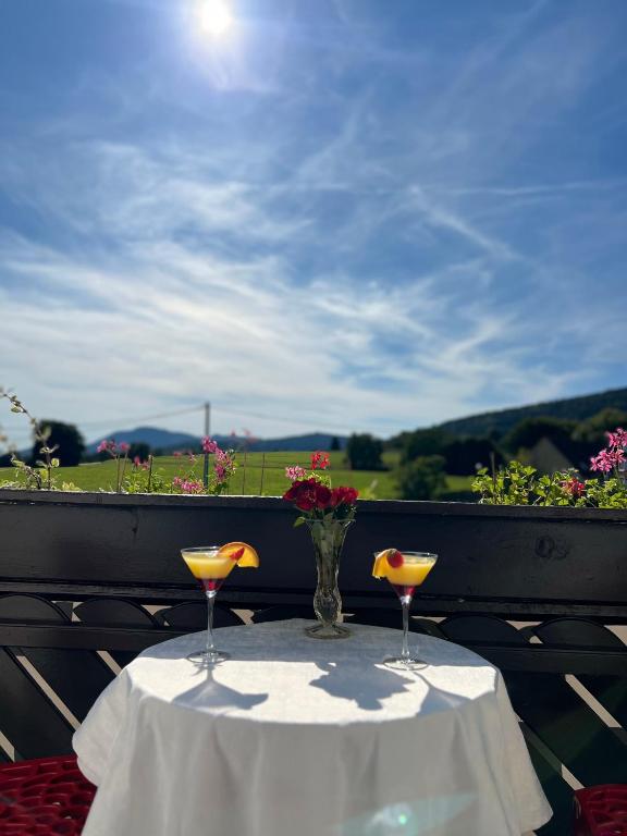 a table with two glasses and a vase with flowers on it at Hôtel l'Orée des Roches in Saales