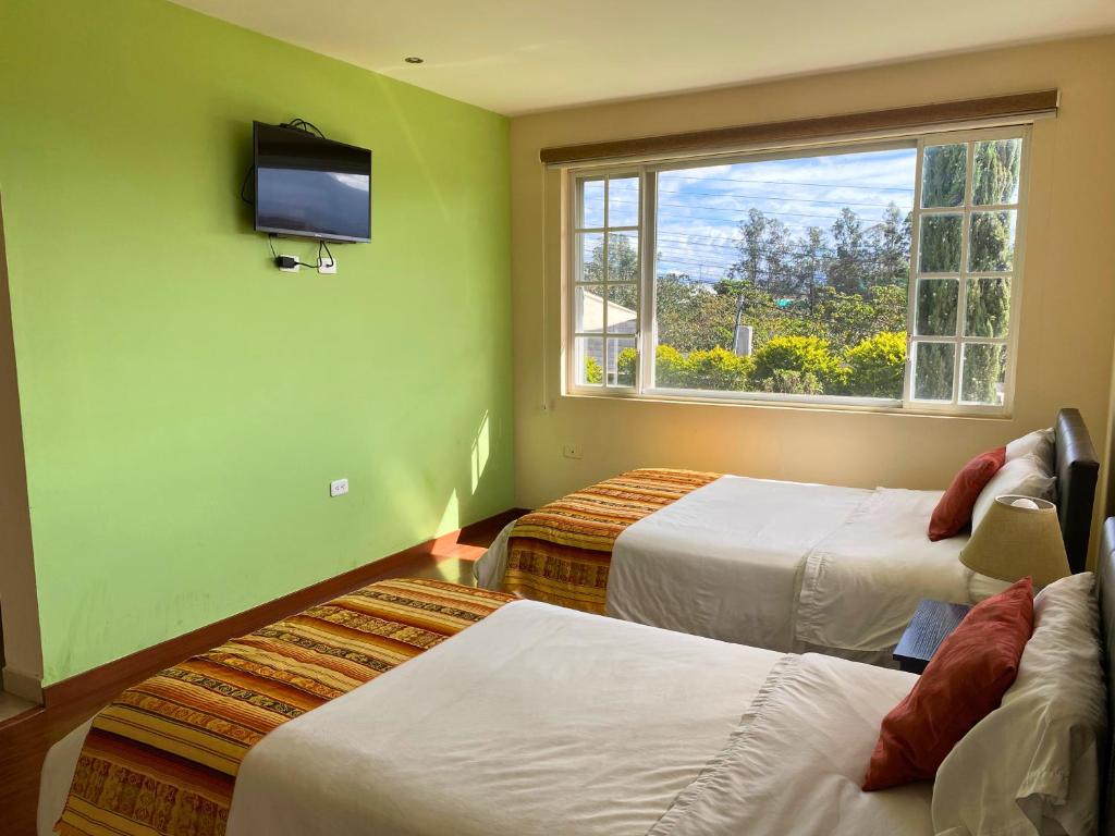 a room with two beds and a flat screen tv at Las Hortensia's Casa De Huespedes in Tababela