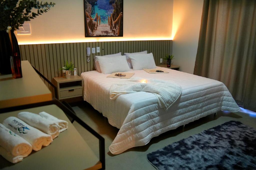 una camera con letto e tavolo con asciugamani di Hotel & Pousada Porto Ubá a Lidianópolis