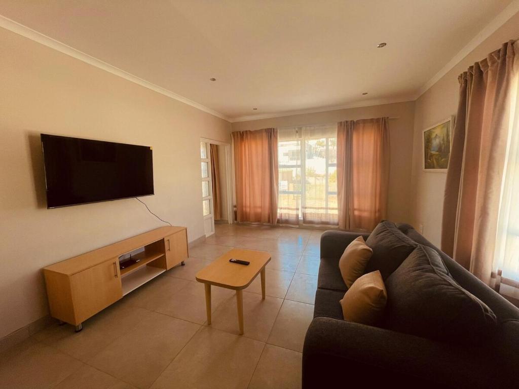 a living room with a couch and a flat screen tv at Biz & Bliss Work & Serene Views in Windhoek