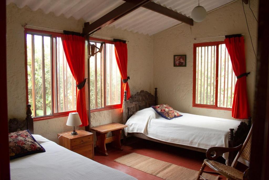 a bedroom with two beds and windows with red curtains at Casa de campo en medio de encantadores jardines in San Francisco