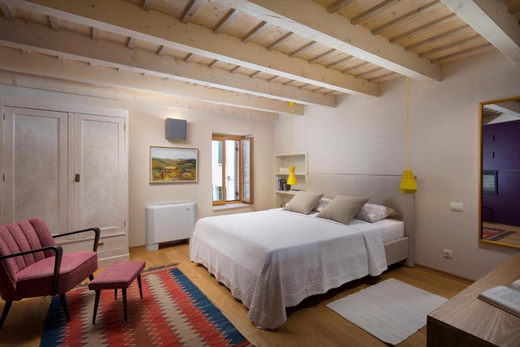 a bedroom with a white bed and a red chair at Holiday Home Bo in Rovinj