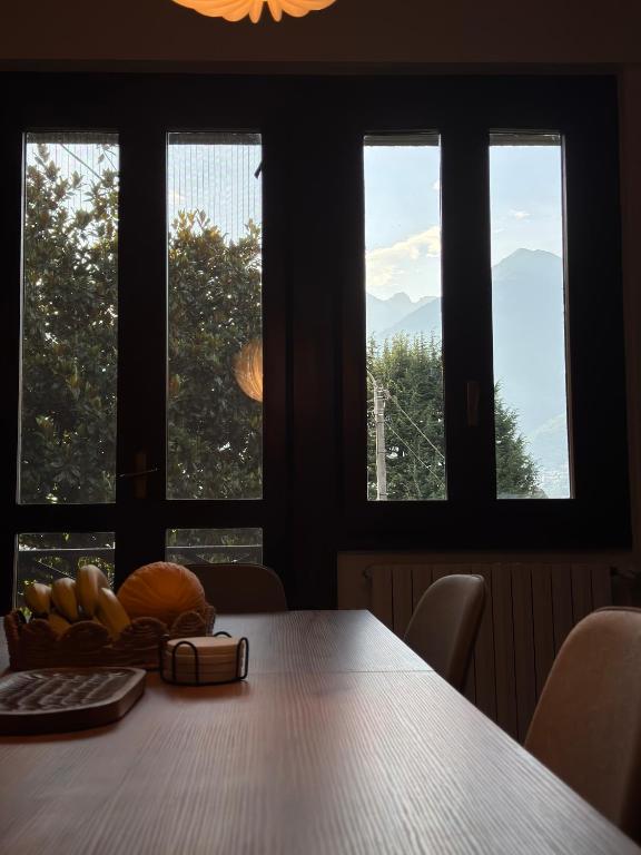 a table with a plate of fruit on it in front of windows at Il cuore della Valtellina - giardino privato in Caiolo