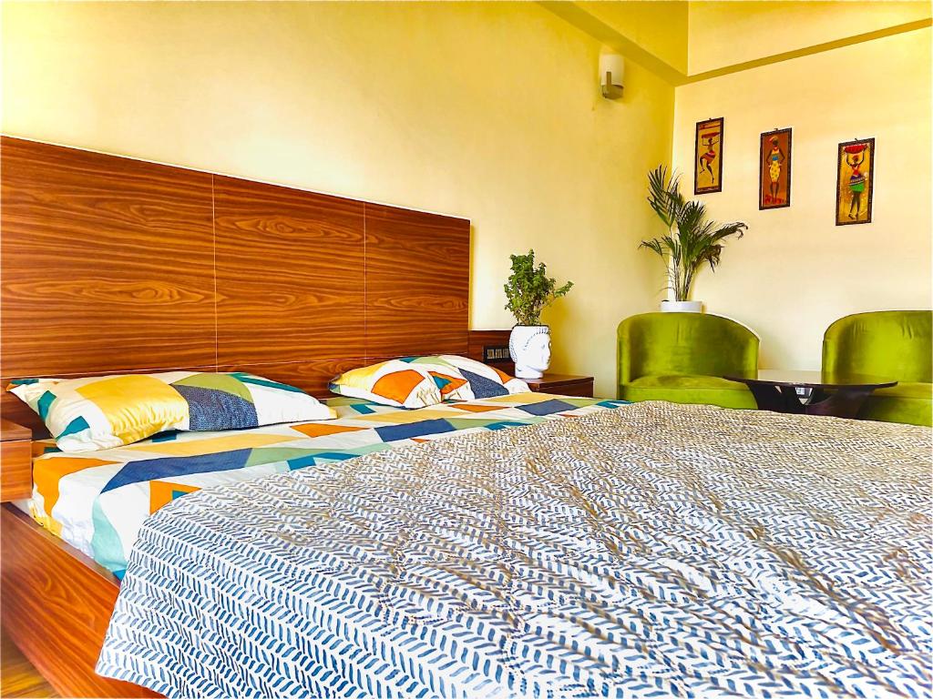 a bedroom with a large bed and two green chairs at Skydeck by 2nd Homes in Dehradun