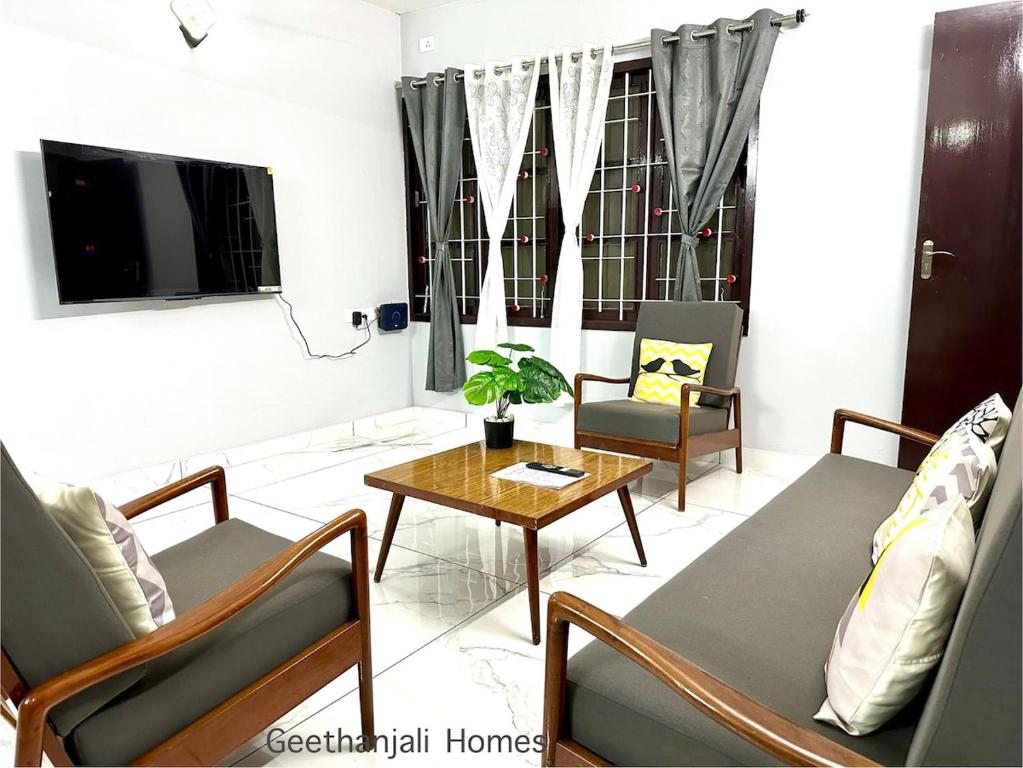 a living room with chairs and a table and a tv at Geethanjali Homes in Kanyakumari