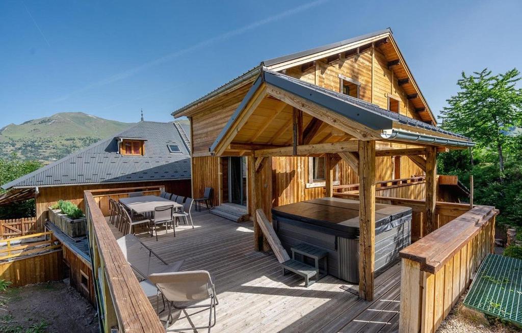 eine große Holzterrasse mit einem Tisch und einem Grill in der Unterkunft Chalet Le Petit Bes by Leavetown Vacations in Les Deux Alpes