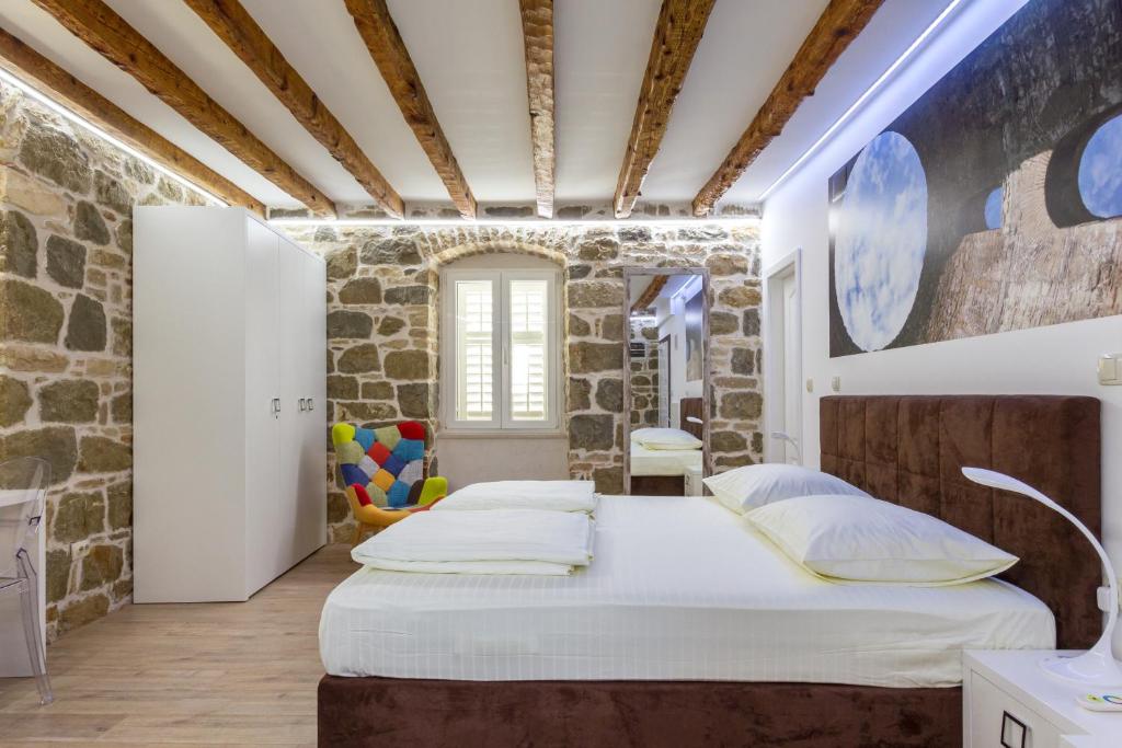 a bedroom with two beds and a stone wall at Studio Central in Split