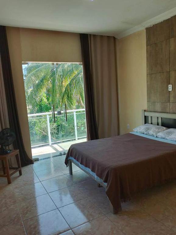 a bedroom with a bed and a large window at Refugio Kitesurf - ilha do Guajirú in Itarema