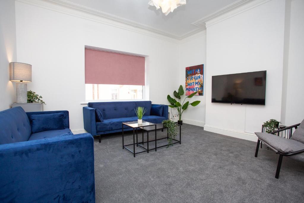 a living room with blue couches and a tv at Vacant Nests The Fredrick Close To Sea Front in Seaham
