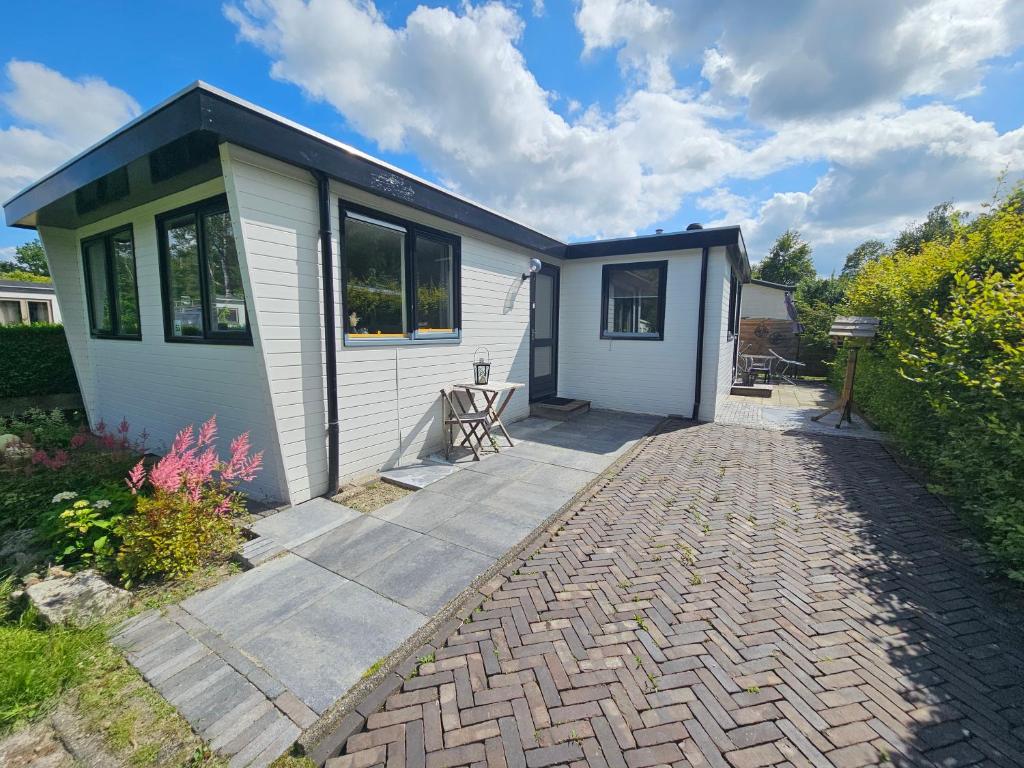 a small white house with a brick driveway at Chalet het zonnehuisje 3 slaapkamers in Appelscha