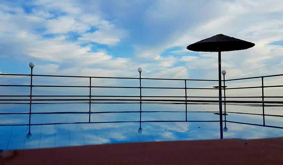 una piscina con sombrilla y el cielo en Asteras Studios, en Argostoli