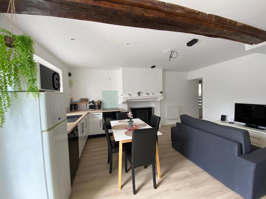 a kitchen and living room with a table and a couch at Petite maison de bourg in Le Bourgneuf-la-Forêt