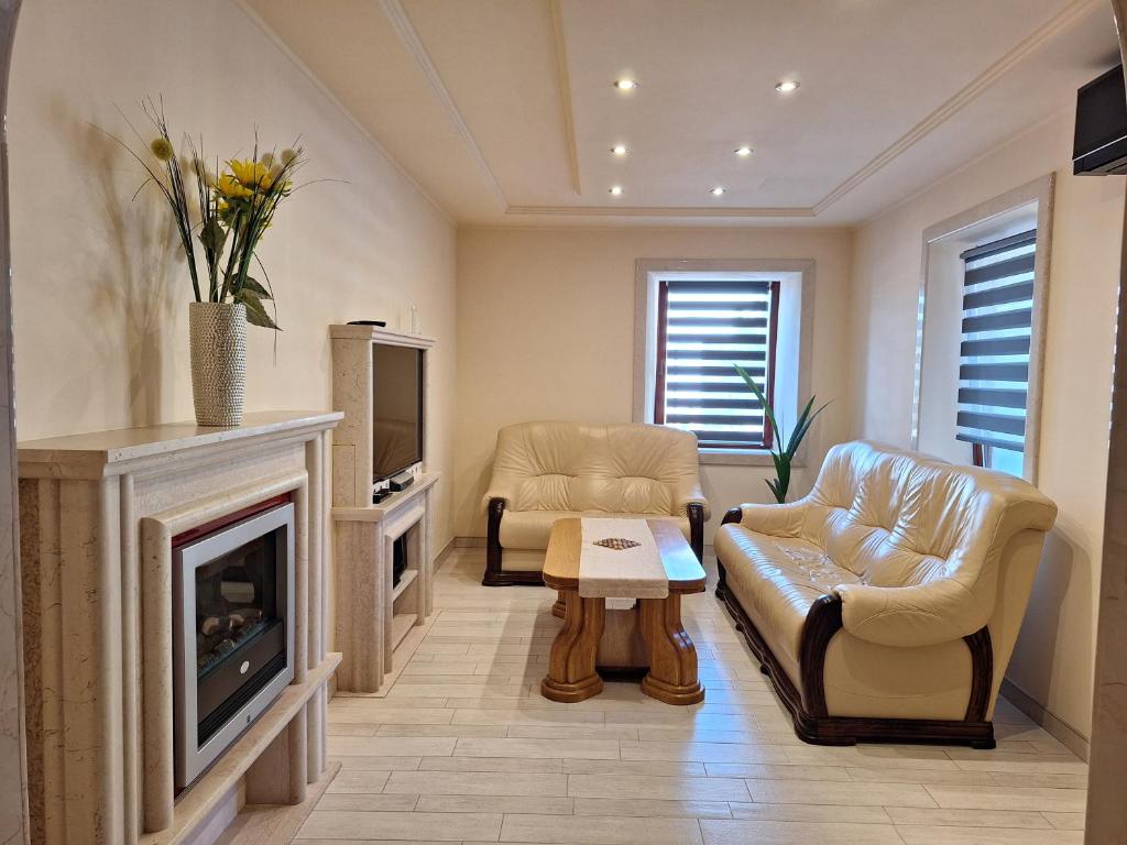 a living room with two chairs and a fireplace at Apartmani IBRA in Lucija