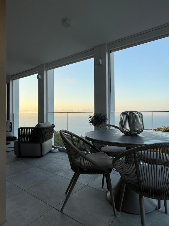 a dining room with a table and chairs and windows at 2-bedroom apartment with breathtaking ocean view in Éze