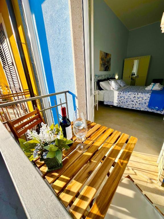 a wooden table with wine glasses and flowers on a balcony at a casa rà Palumma Rooms in Avola