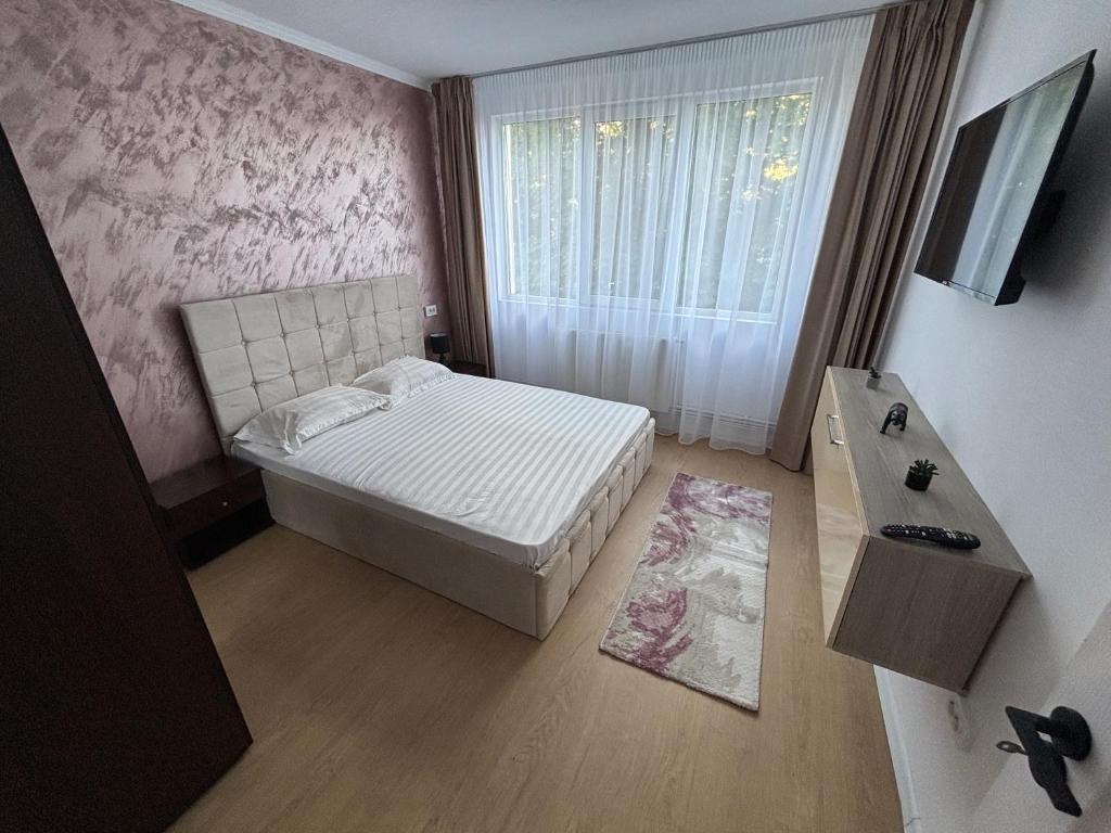 a small bedroom with a bed and a window at Apartment Central in Onești