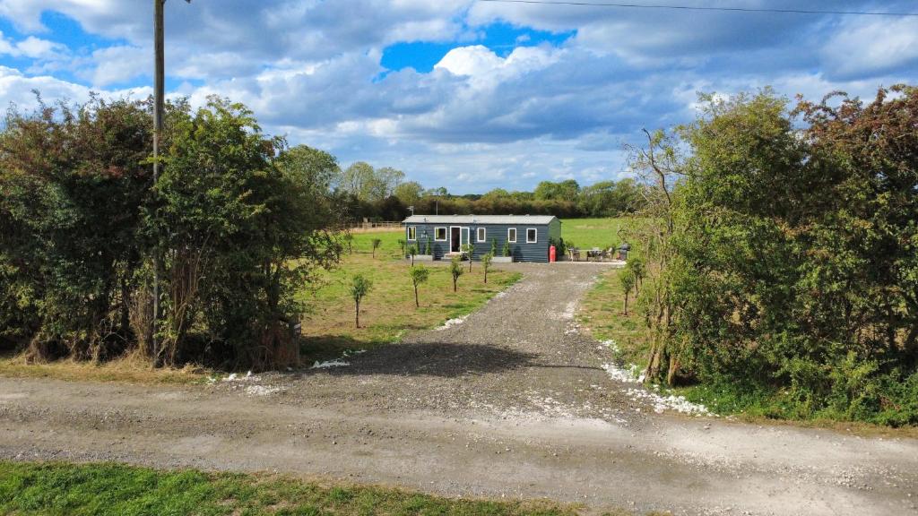 a house in a field with a dirt road at Sheepy Lodge by SkyBears Holidays - Puppy Lounge, Arcades, Games room in Faldingworth