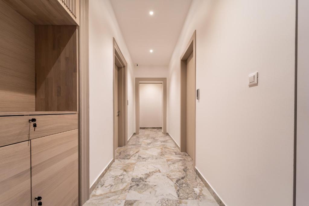 スプリトにあるTifani Luxury Rooms 3の白い壁と大理石の床の廊下とキャビネットのある廊下