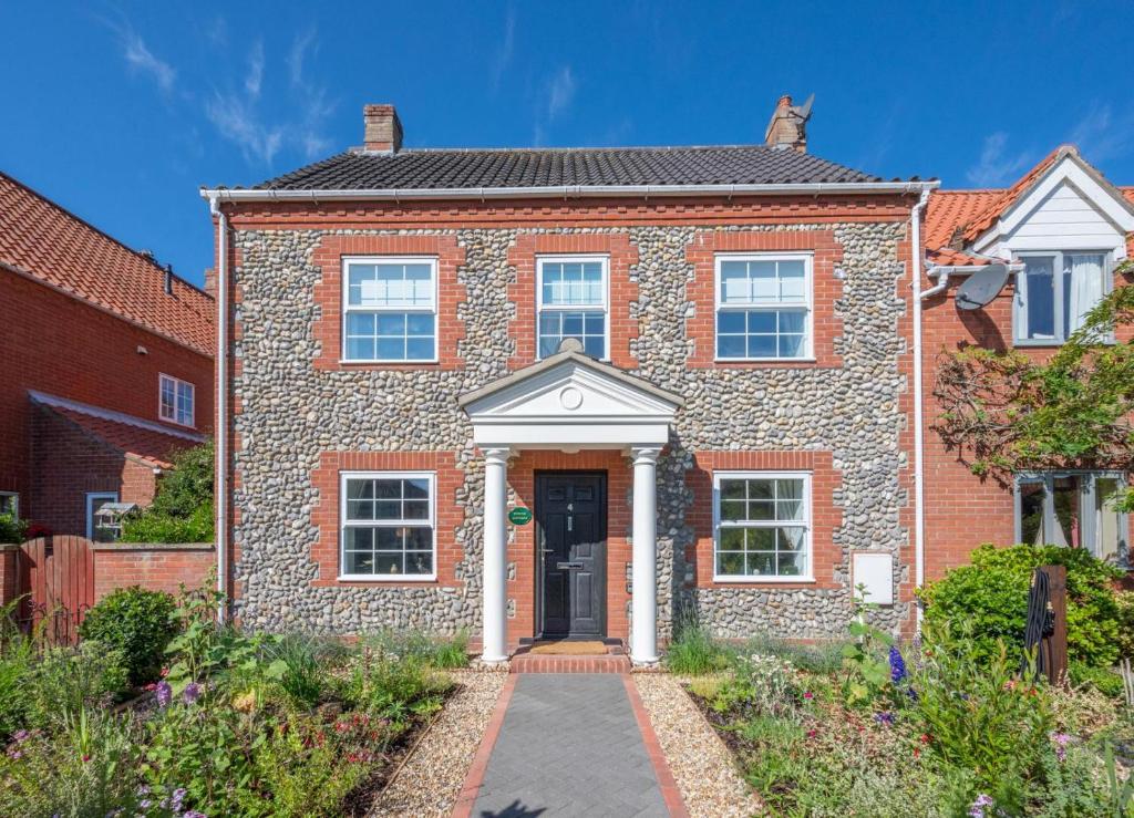a red brick house with a white door at Pound Cottage in Holt