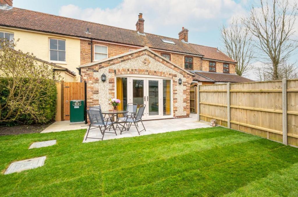 a backyard with a fence and a table and chairs at 2 Wissett Cottages in Aldeby