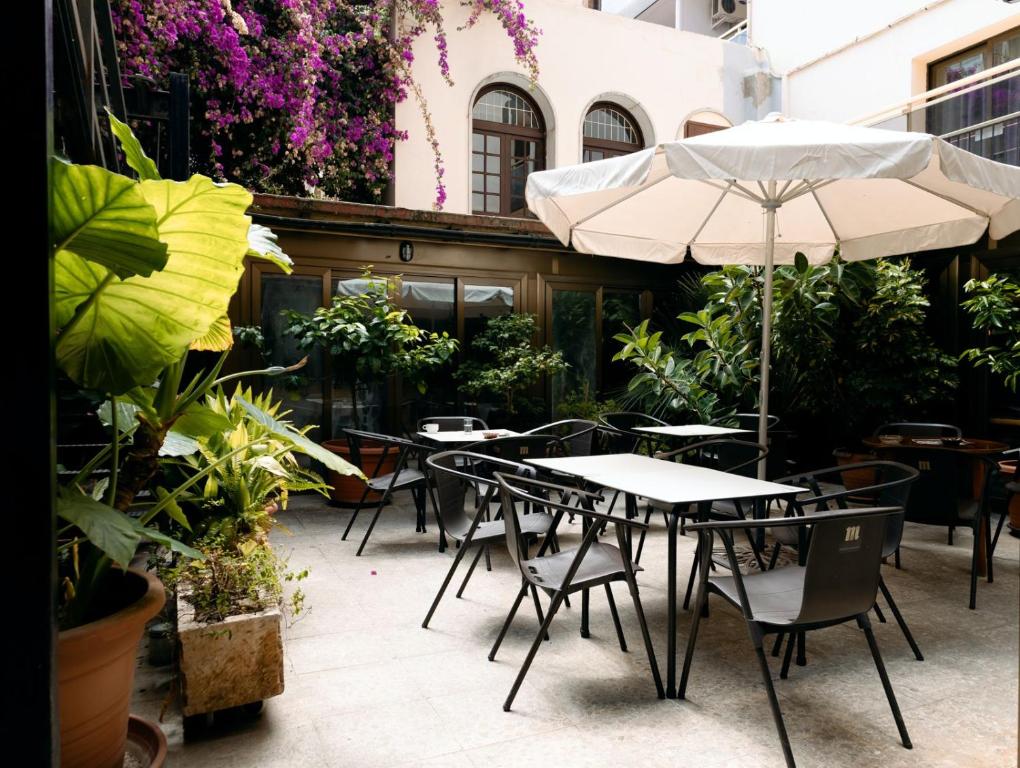 a patio with tables and chairs and an umbrella at Vintage Hotel Mercedes in Lloret de Mar