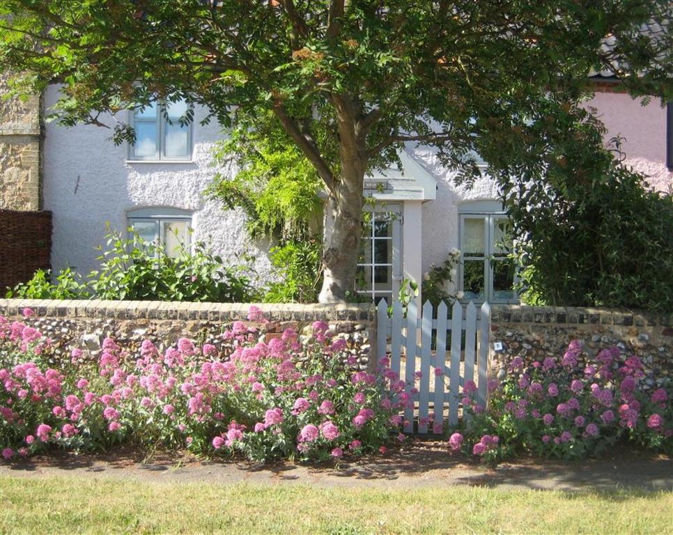 een wit hek voor een huis met roze bloemen bij Box Cottage in Snape