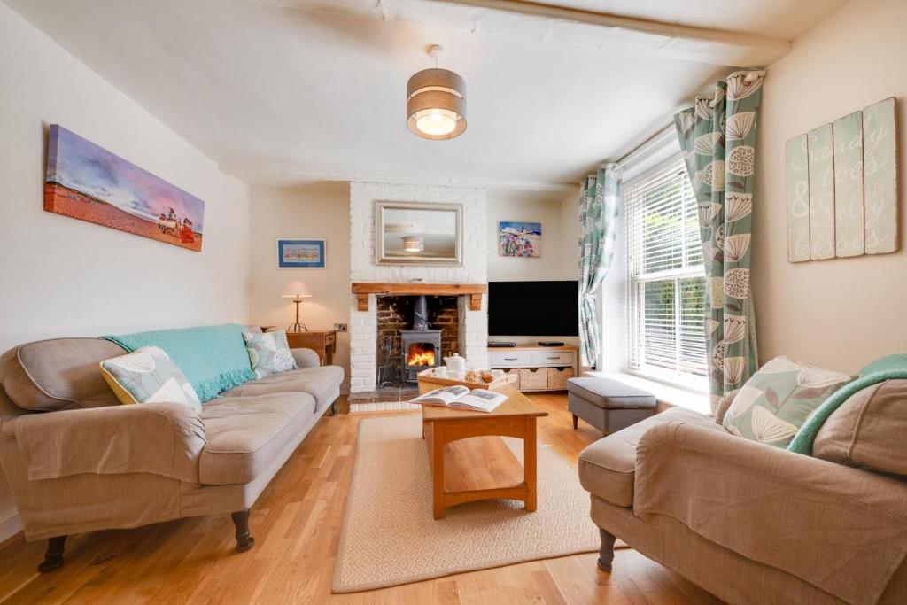 ein Wohnzimmer mit Sofa und Kamin in der Unterkunft Fishermen's Cottage in Sheringham