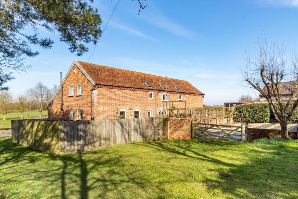 a brick house with a fence in a yard at East Barn Cottage in Aldringham