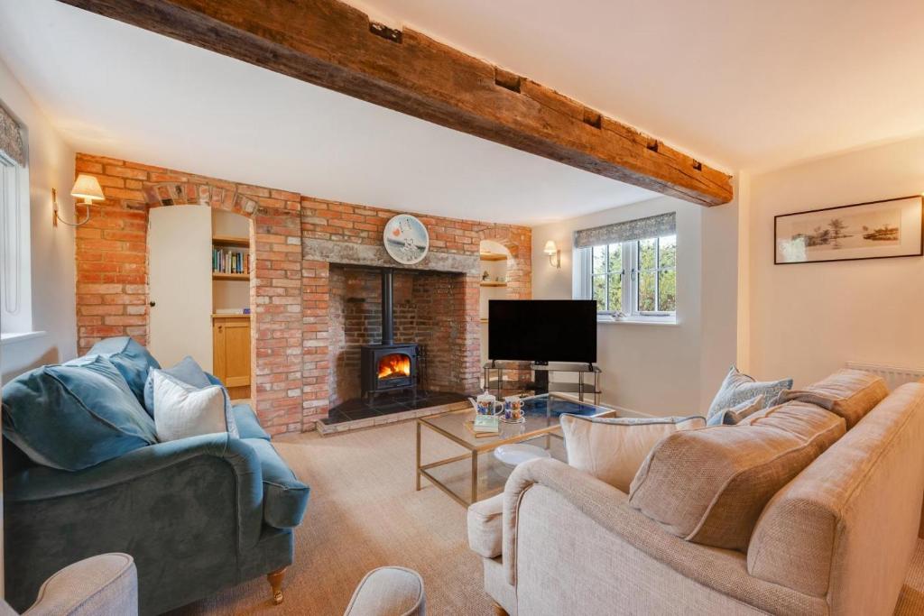 Una sala de estar con dos sofás y una chimenea. en 1 The Homestead, en Frostenden