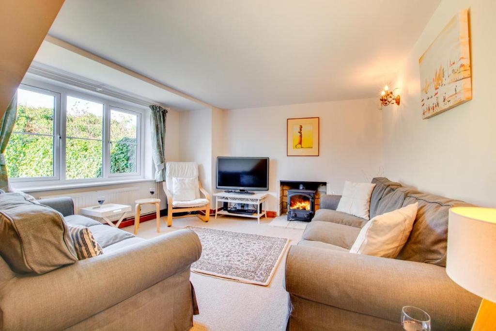 ein Wohnzimmer mit zwei Sofas und einem Fernseher in der Unterkunft Haven Cottage in South Walsham