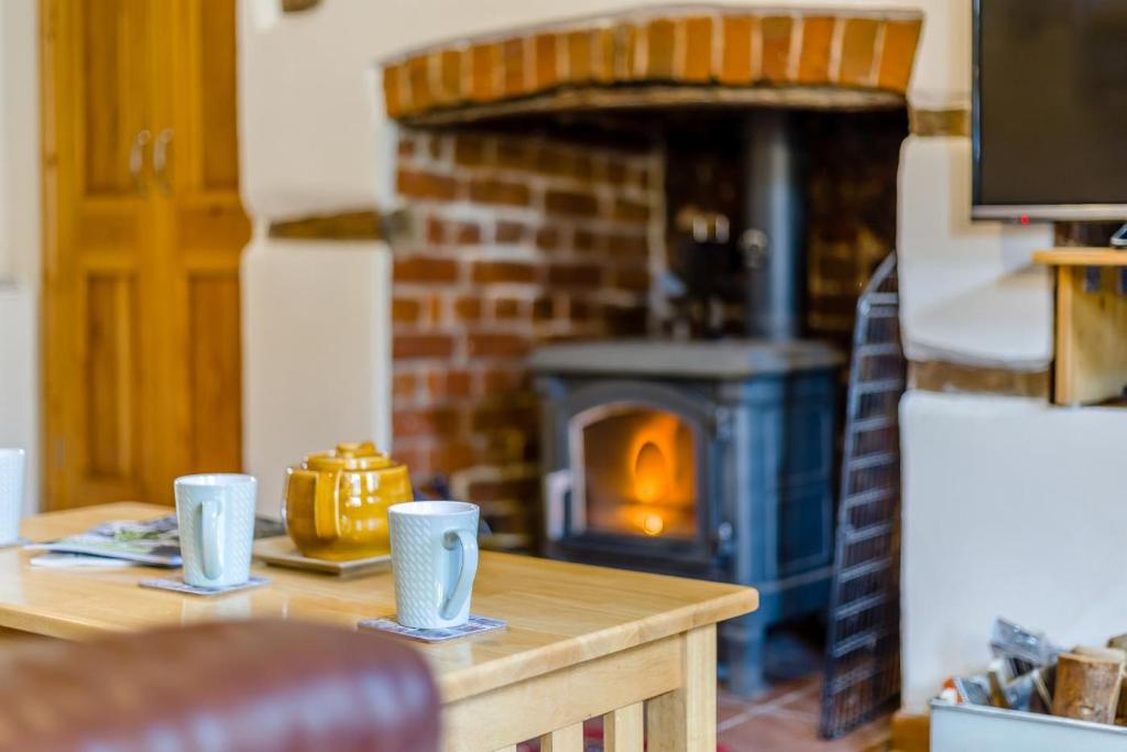 a table with two cups and a brick oven at 3 Church Street in Reepham