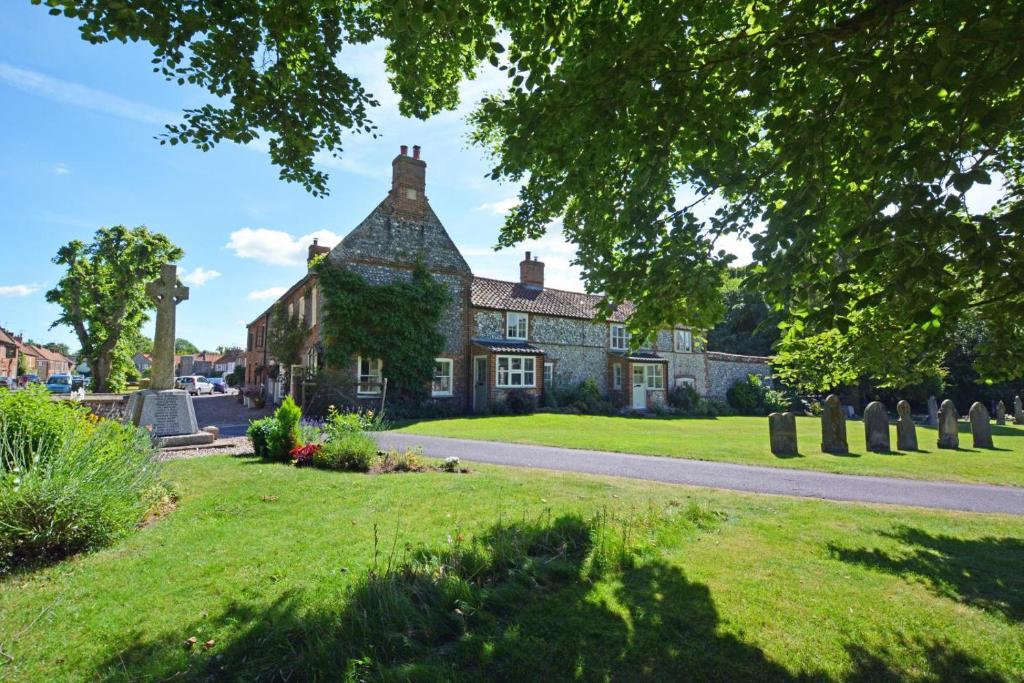 an old stone house on a green lawn at Cockleshells in Castle Acre