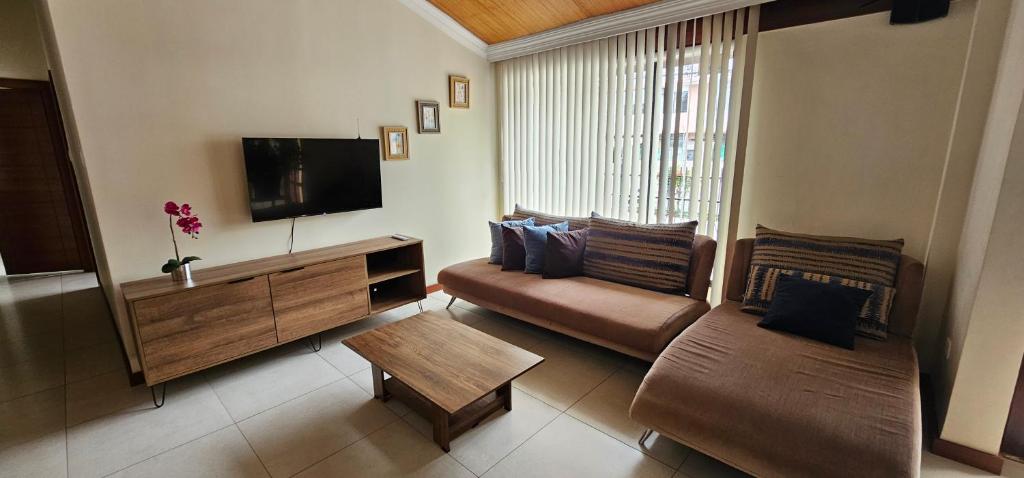 ein Wohnzimmer mit Sofa und Flachbildfernseher in der Unterkunft Altamira Apart Suites in Quito