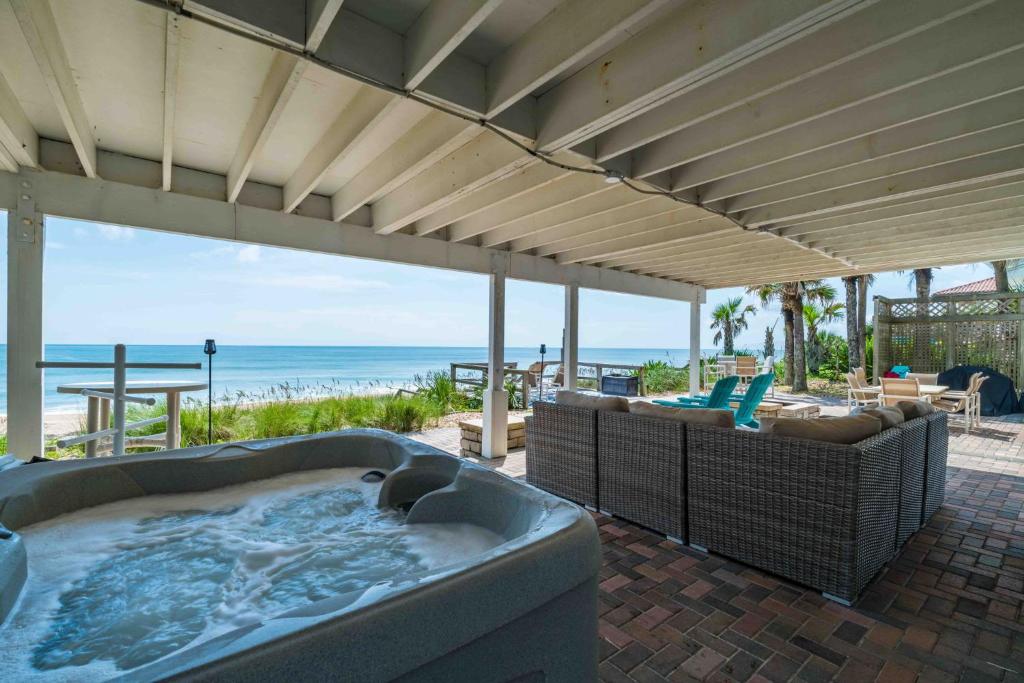 un patio con bañera de hidromasaje y vistas a la playa en Gone Coastal - Oceanfront Home with a Hotub, en Ponte Vedra Beach