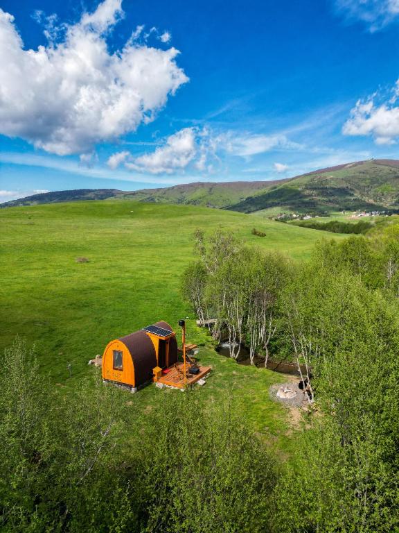 an orange tent in the middle of a green field at RAZBIBRIGA - Riverside Camping Pod by IGLENA in Kupres