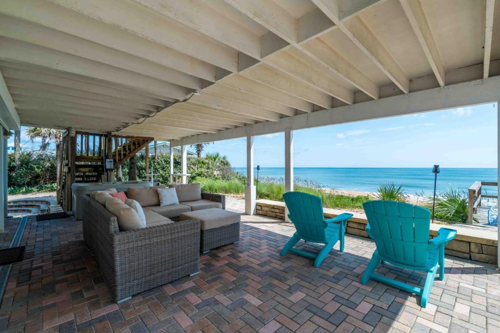 a patio with a couch and chairs and the ocean at Gone Coastal - Oceanfront Home with a Hotub in Ponte Vedra Beach