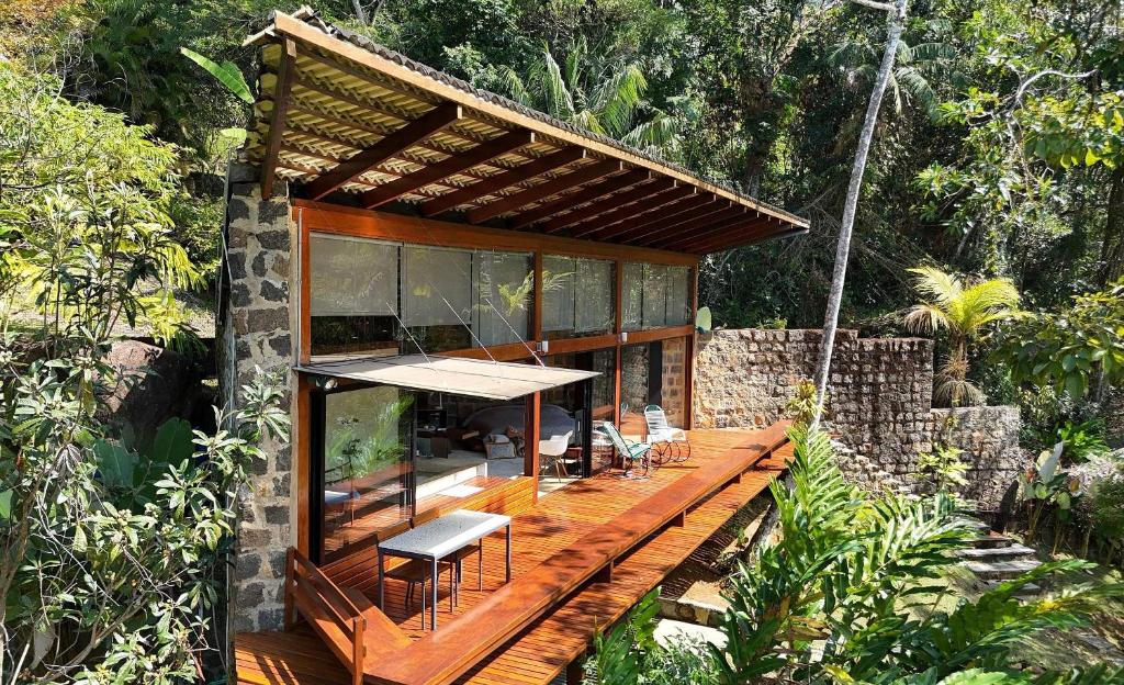 a house with a wooden deck in the forest at Mirante do Leo - Casa com Piscina Aquecida e Loft Exclusivo com Vista para o Mar in Ubatuba