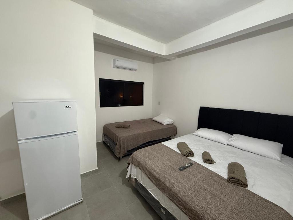 a small room with two beds and a refrigerator at Departamentos Imperial in Encarnación