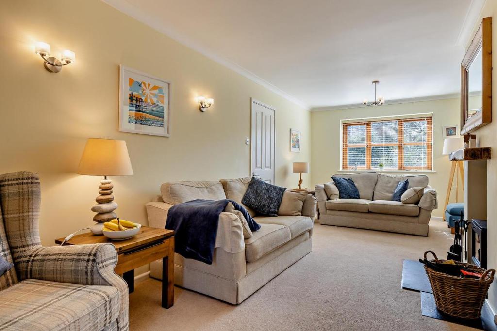 a living room with two couches and a table at 1 Street Farm Cottages in Bodham